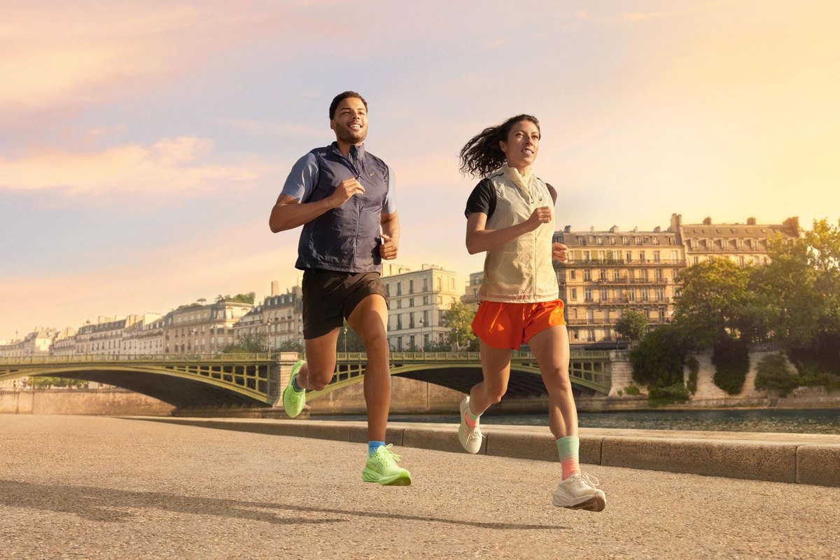 Two runners crossing a bridge in Paris at dawn in ASICS shoes