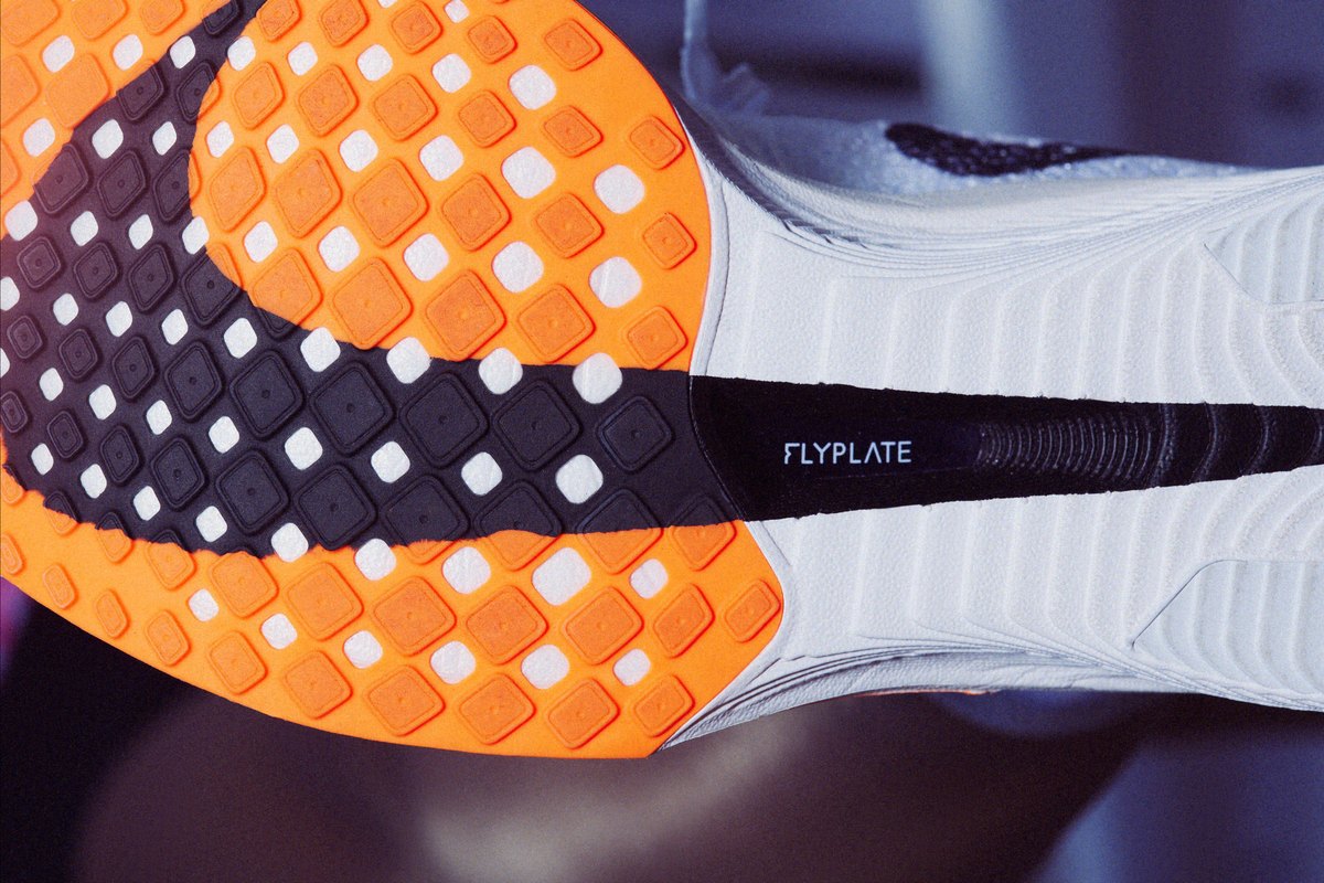 The outsole of a Nike Vaporfly 3 from below: orange rubber, and a black window in the midsole showing the carbon plate, labelled Flyplate