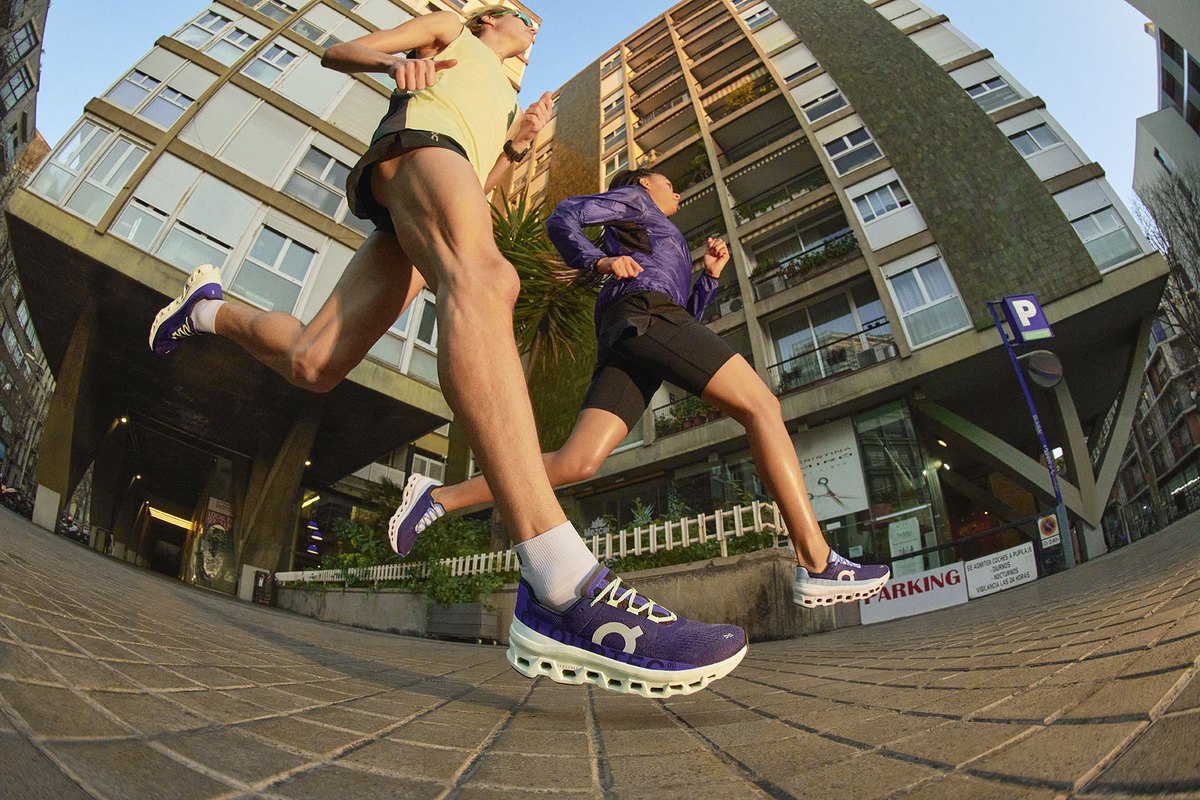 Runners in purple On shoes mid-stride on a city street, shot from ground level
